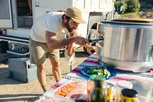Homme utilisant glacière Dometic CFX2 devant camping-car avec repas préparé