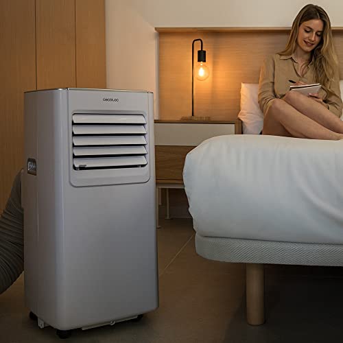 Climatiseur Cecotec dans chambre moderne avec femme lisant sur lit, éclairage tamisé