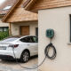 Borne de recharge murale installée sur la façade d'une maison, voiture électrique branchée en charge à domicile