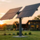 Tracker solaire deux axes à quatre panneaux dans un jardin de particulier au coucher du soleil