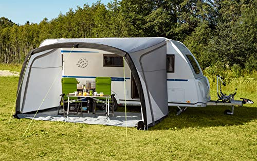 Auvent gonflable Berger Sombra-L installé en camping herbeux avec coin repas ombragé sous les arbres