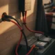 Régulateur de charge solaire mural relié par câbles rouge et noir à une batterie 12 V et à un panneau solaire, à l'intérieur d'un van aménagé