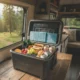 Glacière portable ouverte remplie d'aliments frais et de pains de glace sur une table dans un van, fenêtre ouverte sur la forêt
